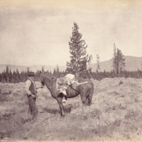 Man holding reins of horse with dead pronghorn on horse's back<br />
