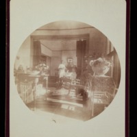 House interior, J.G. Averell in rocker, foreground; unidentified woman in background