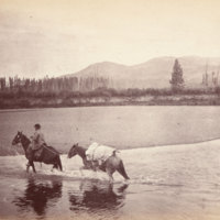 Man on horseback fording stream, leading pack horse<br />
